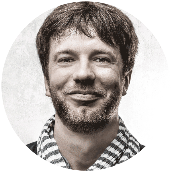Ein Portraifoto von Florian Thomi, Freelancer für Film, Animation und Print. Frontal in die Kamera schauend und fröhlich grinsend.